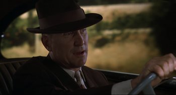 Movie still from “True Confessions” (1981), directed by Ulu Grosbard – An older man wearing a suit and hat driving a car; Close Up shot, Over the shoulder angle