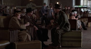Movie still from “True Confessions” (1981), directed by Ulu Grosbard – A group of men sitting on top of suitcases in a room; Wide shot, High angle