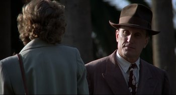 Movie still from “True Confessions” (1981), directed by Ulu Grosbard – A man in a suit and a hat talking to a woman; Close Up shot, Over the shoulder angle