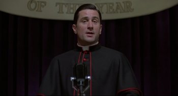 Movie still from “True Confessions” (1981), directed by Ulu Grosbard – A man wearing a black and red clergy robe; Close Up shot, Low angle