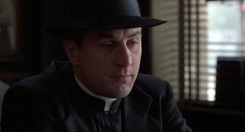 Movie still from “True Confessions” (1981), directed by Ulu Grosbard – A man wearing a hat and a priest's outfit; Close Up shot, Low angle