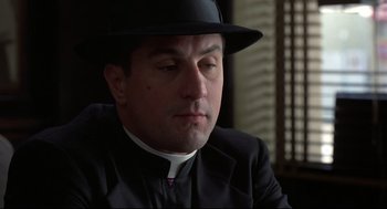 Movie still from “True Confessions” (1981), directed by Ulu Grosbard – A man wearing a hat and a priest's outfit; Close Up shot, Low angle