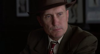 Movie still from “True Confessions” (1981), directed by Ulu Grosbard – A person wearing a suit and a hat; Close Up shot, Low angle
