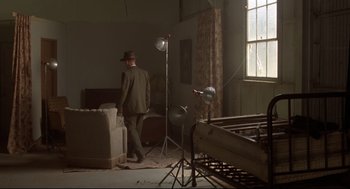 Movie still from “True Confessions” (1981), directed by Ulu Grosbard – A man in a suit and hat in a room; Wide shot, High angle