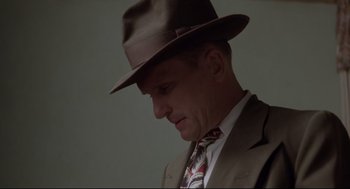 Movie still from “True Confessions” (1981), directed by Ulu Grosbard – A man in a suit and a hat is looking down at his face; Close Up shot, Low angle