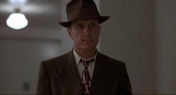 Movie still from “True Confessions” (1981), directed by Ulu Grosbard – A man in a suit and hat is looking at the camera; Close Up shot, Low angle