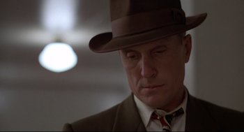 Movie still from “True Confessions” (1981), directed by Ulu Grosbard – A person wearing a suit and a hat; Close Up shot, Low angle