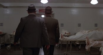Movie still from “True Confessions” (1981), directed by Ulu Grosbard – Two men in suits and hats walk away from a hospital bed; Wide shot, Low angle