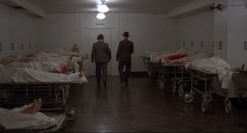 Movie still from “True Confessions” (1981), directed by Ulu Grosbard – A couple of men walking in a room next to a bunch of beds; Wide shot, High angle