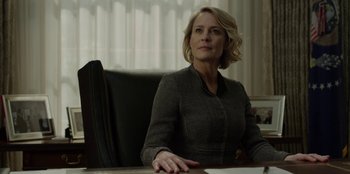 Movie still from “House of Cards” (2013), created by Beau Willimon – A woman sitting at a table in a room; Close Up shot, Low angle