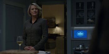 Movie still from “House of Cards” (2013), created by Beau Willimon – A woman standing in front of a tv in a room; Medium shot, Over the shoulder angle