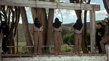 Movie still from “True Grit” (1969), directed by Henry Hathaway – A group of people standing next to a tree; Wide shot, Low angle
