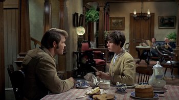 Movie still from “True Grit” (1969), directed by Henry Hathaway – Two people sitting at a table in a room; Medium shot, Over the shoulder angle