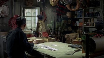 Movie still from “True Grit” (1969), directed by Henry Hathaway – A man sitting at a table in a room; Wide shot, High angle