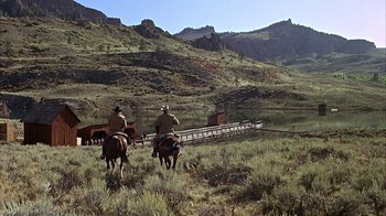 Movie still from “True Grit” (1969), directed by Henry Hathaway – Two men on horses in the middle of a grassy field; Extreme Wide shot, Low angle