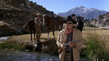 Movie still from “True Grit” (1969), directed by Henry Hathaway – A group of men standing next to horses in a field; Wide shot, Over the shoulder angle