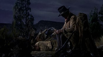 Movie still from “True Grit” (1969), directed by Henry Hathaway – A man in a cowboy hat sitting next to a dead man; Wide shot, Low angle