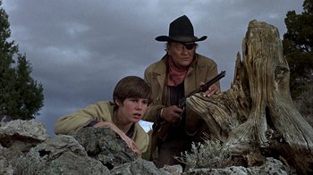 Movie still from “True Grit” (1969), directed by Henry Hathaway – A man and a young boy with a gun in a field; Medium shot, Low angle