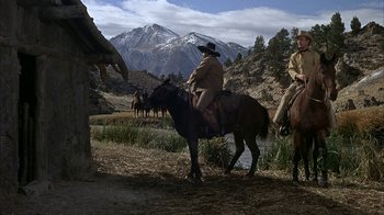 Movie still from “True Grit” (1969), directed by Henry Hathaway – Two men on horses in a field with mountains in the background; Wide shot, Low angle