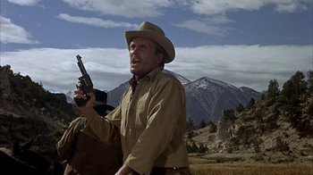 Movie still from “True Grit” (1969), directed by Henry Hathaway – A man holding a gun while standing in a field; Medium shot, Low angle