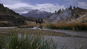 Movie still from “True Grit” (1969), directed by Henry Hathaway – Two people on horseback crossing a river in the mountains; Extreme Wide shot, High angle