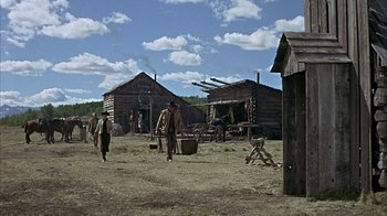 Movie still from “True Grit” (1969), directed by Henry Hathaway – A group of people standing in a dirt field near some buildings; Extreme Wide shot, Low angle