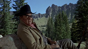 Movie still from “True Grit” (1969), directed by Henry Hathaway – An older man sitting on the ground in a cowboy hat; Medium shot, Low angle
