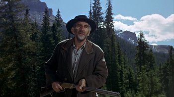 Movie still from “True Grit” (1969), directed by Henry Hathaway – An old man holding a rifle in a forest; Medium shot, Low angle