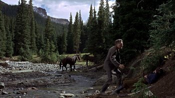 Movie still from “True Grit” (1969), directed by Henry Hathaway – A man and two horses in the mountains; Wide shot, Low angle