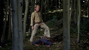 Movie still from “True Grit” (1969), directed by Henry Hathaway – A man standing next to a dead body in the woods; Medium shot, Low angle