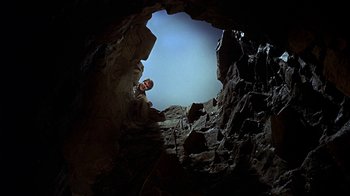 Movie still from “True Grit” (1969), directed by Henry Hathaway – A person in a cave looking out at the sky; Wide shot, Low angle