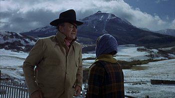 Movie still from “True Grit” (1969), directed by Henry Hathaway – A man and a woman standing next to each other in front of a snowy mountain; Medium shot, Over the shoulder angle