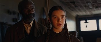 Movie still from “True Grit” (2010), directed by Ethan Coen – A young girl with plaited pigtails standing next to an older man; Close Up shot, Over the shoulder angle