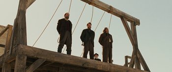 Movie still from “True Grit” (2010), directed by Ethan Coen – A group of men standing on top of a wooden structure; Wide shot, Low angle