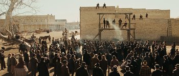 Movie still from “True Grit” (2010), directed by Ethan Coen – A crowd of people standing around a building; Extreme Wide shot, Low angle