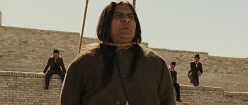 Movie still from “True Grit” (2010), directed by Ethan Coen – A man with long black hair wearing a brown jacket; Medium shot, Low angle
