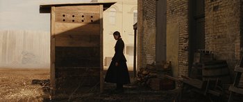 Movie still from “True Grit” (2010), directed by Ethan Coen – A woman standing in an old building in the sunlight; Wide shot, Over the shoulder angle