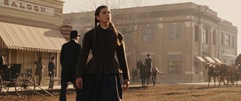 Movie still from “True Grit” (2010), directed by Ethan Coen – A woman in a brown coat and a black skirt; Medium shot, Low angle