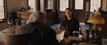 Movie still from “True Grit” (2010), directed by Ethan Coen – A woman sitting at a table with a man; Medium shot, Over the shoulder angle