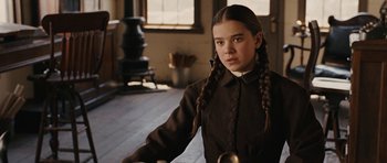 Movie still from “True Grit” (2010), directed by Ethan Coen – A young girl with braids in a room; Close Up shot, Over the shoulder angle