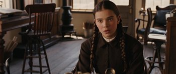 Movie still from “True Grit” (2010), directed by Ethan Coen – A young girl with braids sitting in a room; Close Up shot, High angle