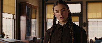 Movie still from “True Grit” (2010), directed by Ethan Coen – A young girl with braids in a room; Close Up shot, Low angle