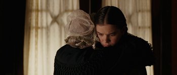 Movie still from “True Grit” (2010), directed by Ethan Coen – A woman is hugging a young girl in a black dress; Close Up shot, Over the shoulder angle