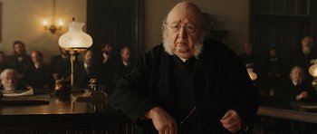 Movie still from “True Grit” (2010), directed by Ethan Coen – An old man with a beard and glasses is holding a pair of scissors; Close Up shot, Over the shoulder angle