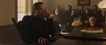 Movie still from “True Grit” (2010), directed by Ethan Coen – An old man sitting at a table with a beard; Medium shot, Over the shoulder angle