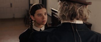 Movie still from “True Grit” (2010), directed by Ethan Coen – A young girl looking at a man in a suit in front of a piano; Close Up shot, Over the shoulder angle
