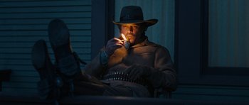 Movie still from “True Grit” (2010), directed by Ethan Coen – A man wearing a hat is lighting a cigarette; Medium shot, Low angle