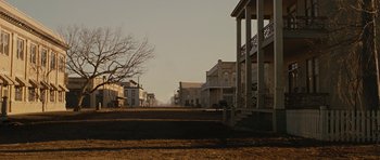 Movie still from “True Grit” (2010), directed by Ethan Coen – An empty dirt road with a row of houses on the side of the road; Extreme Wide shot, High angle