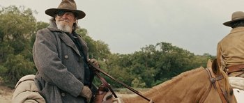 Movie still from “True Grit” (2010), directed by Ethan Coen – A man riding on the back of a brown horse; Medium shot, Over the shoulder angle