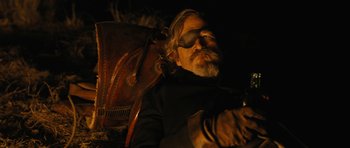 Movie still from “True Grit” (2010), directed by Ethan Coen – A man with long hair and a goatee wearing sunglasses and holding a guitar; Medium shot, Low angle